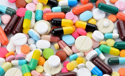 Many pills of different colours scattered all over a surface
